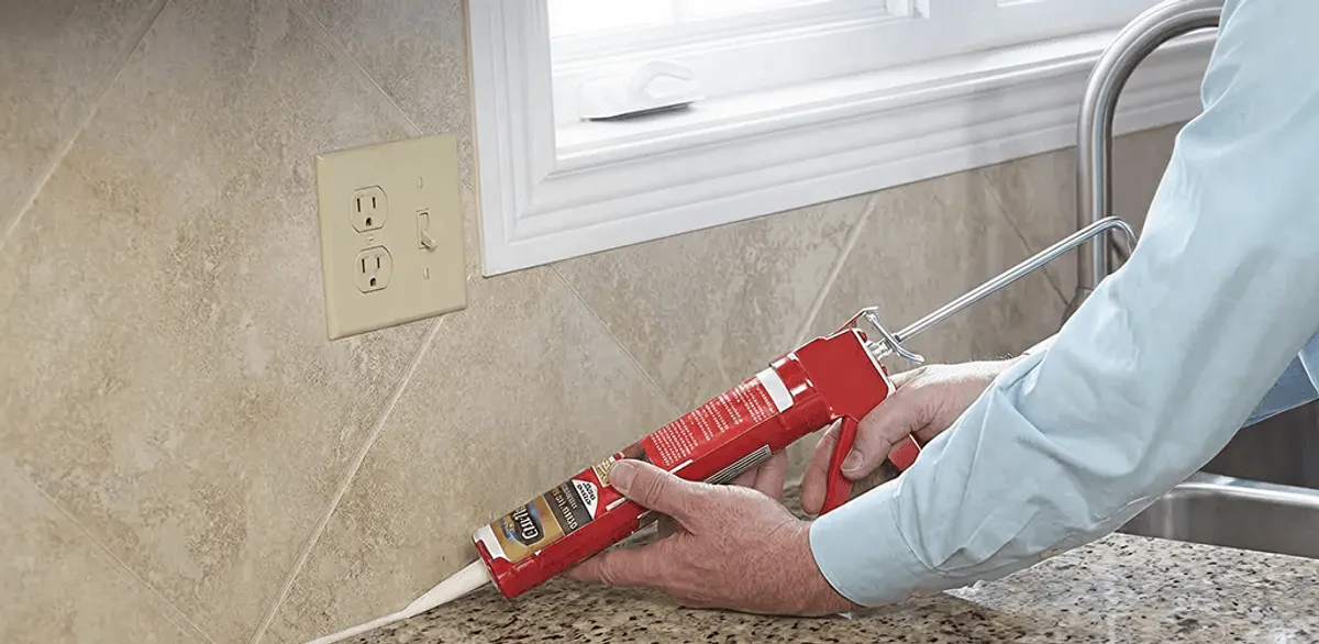 Handyman applying caulk along a kitchen backsplash and countertop seam in Shreveport, LA